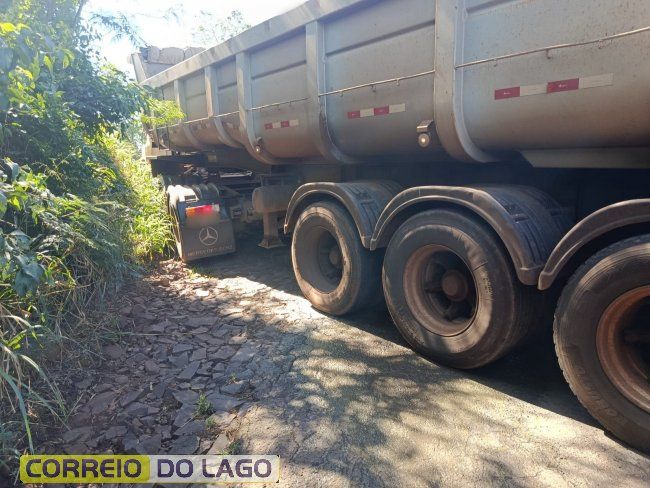 Caminhões de carga parados em trecho de estrada rural de terra em declive com dificuldades de tração