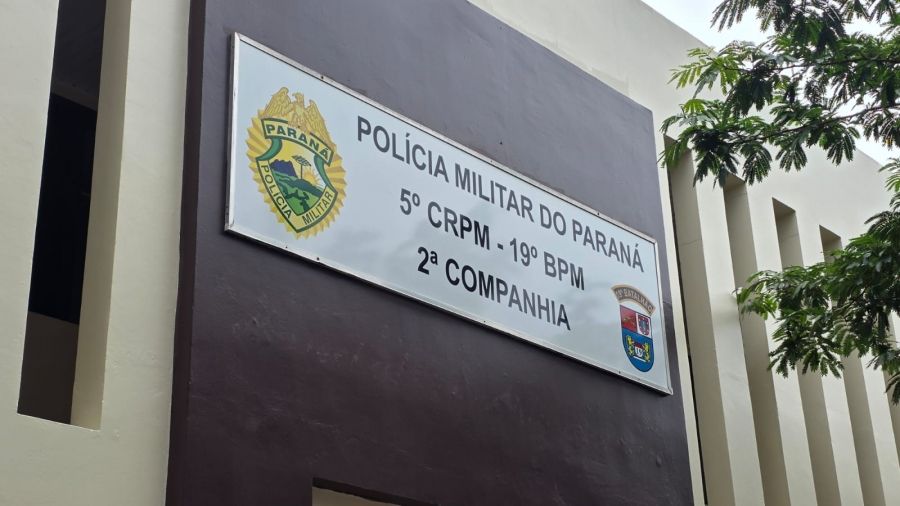 Mulher em desespero gritando por socorro de dentro de um carro em movimento, com parte do corpo para fora da janela, em frente à sede da Polícia Militar.