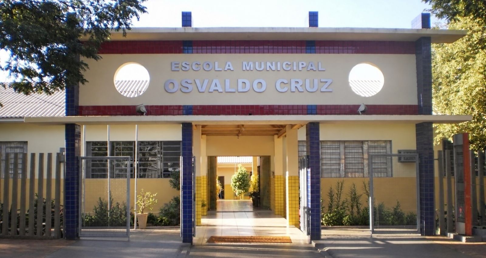 Fachada de uma escola municipal em Toledo com sinalização de segurança e equipe pedagógica em planejamento