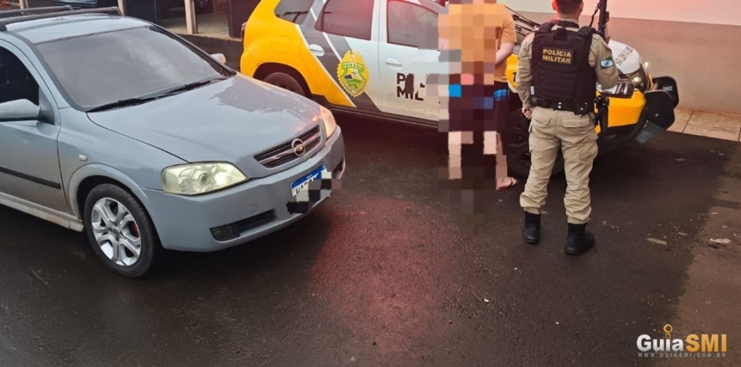 Veículo Chevrolet Astra prata parado em uma estrada rural com policiais militares ao lado.