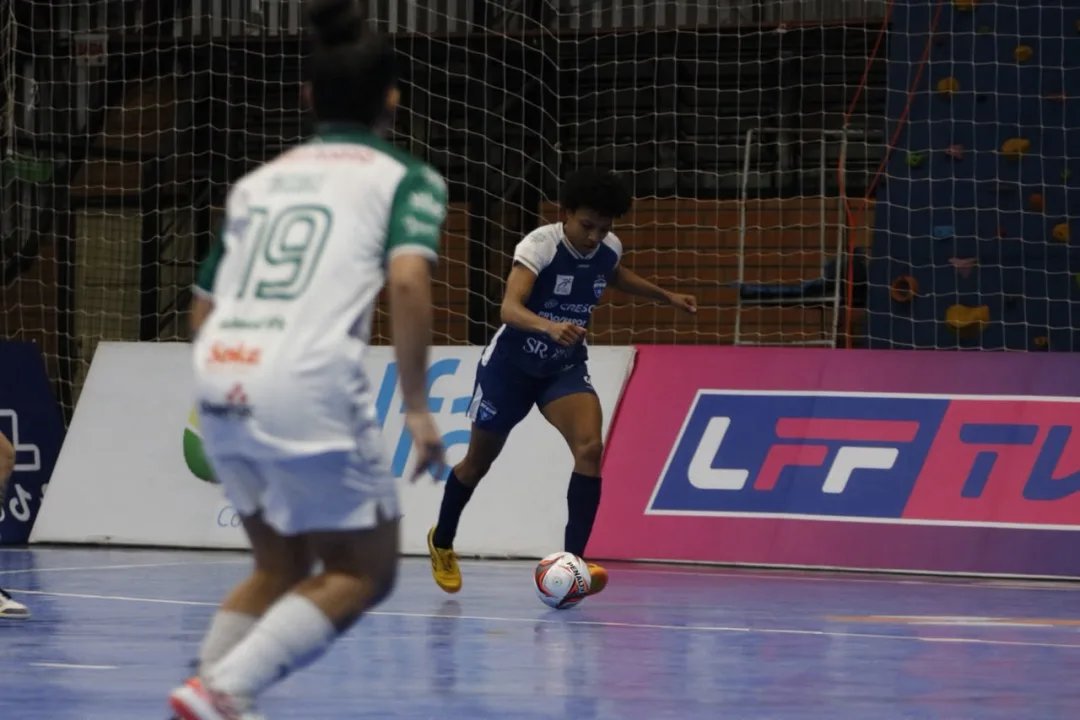 Jogadoras de futsal comemorando um gol em quadra