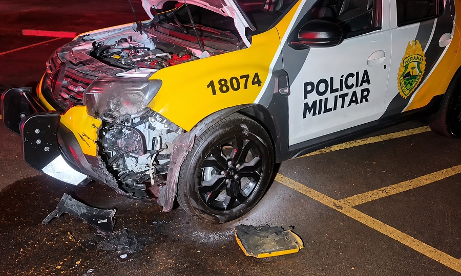 Viatura da Polícia Militar estacionada no Parque Luiz Carlos Hoffmann em Toledo com agentes avaliando os danos na parte dianteira após princípio de incêndio